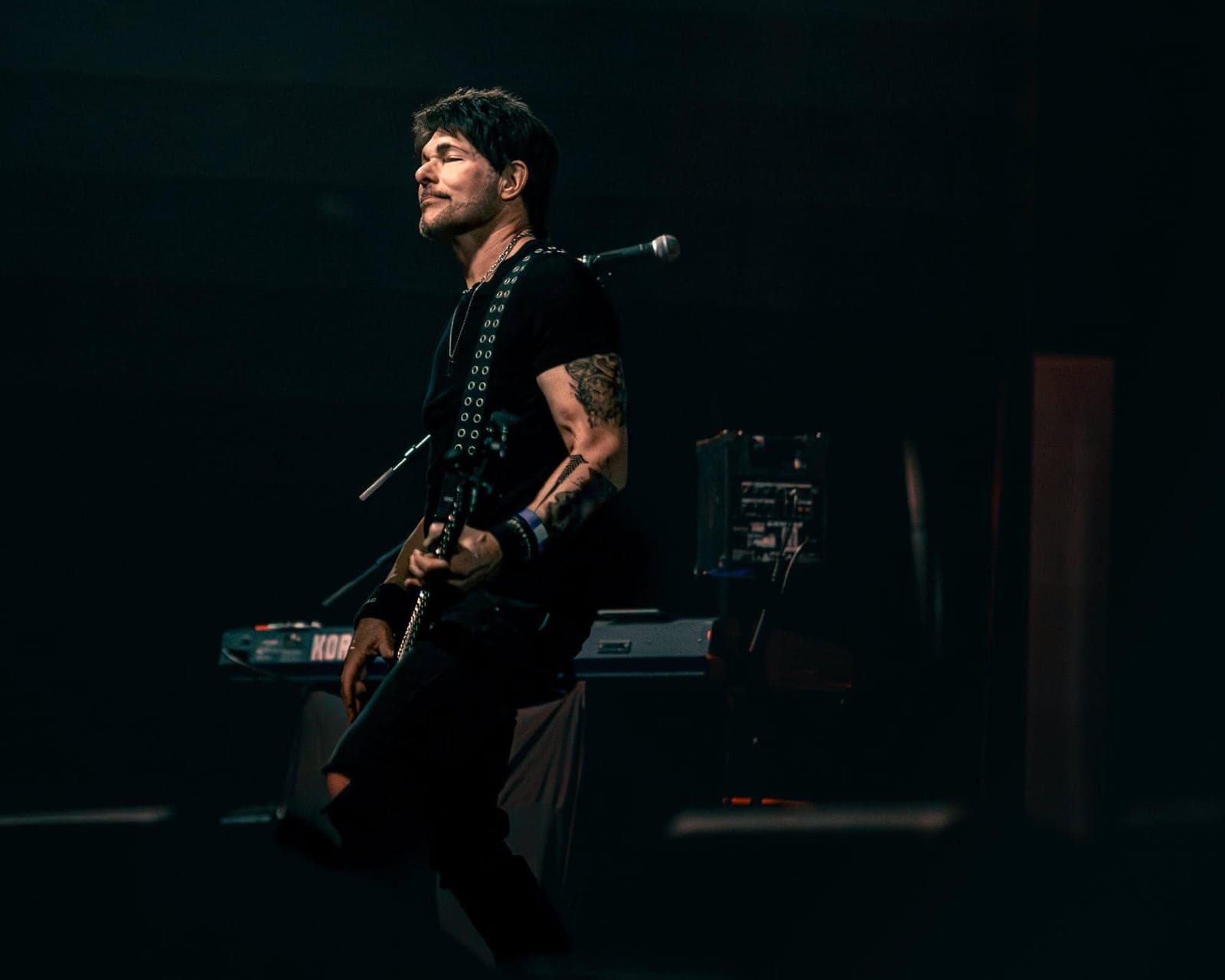 Mikki Seven playing bass on a dark stage